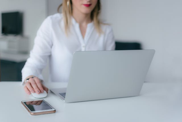 person wearing white while working at their desk on their laptop